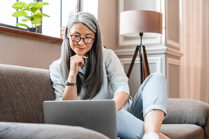 an older woman looking at her laptop at home