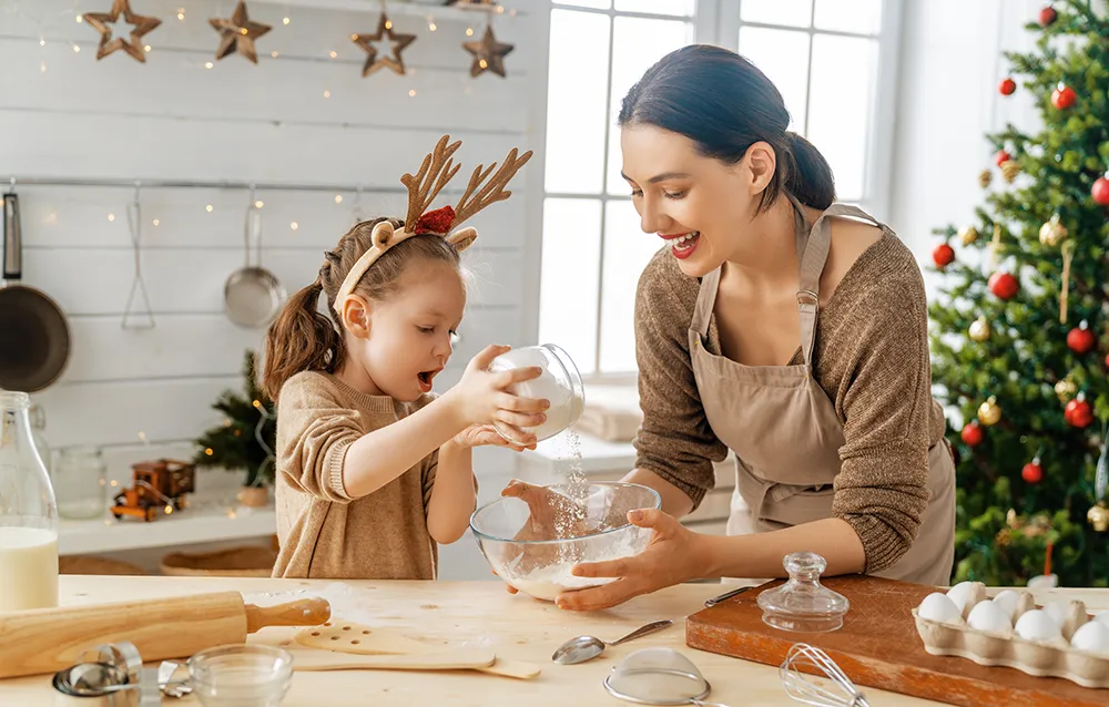 a mom and her young daughter baking cookies at home